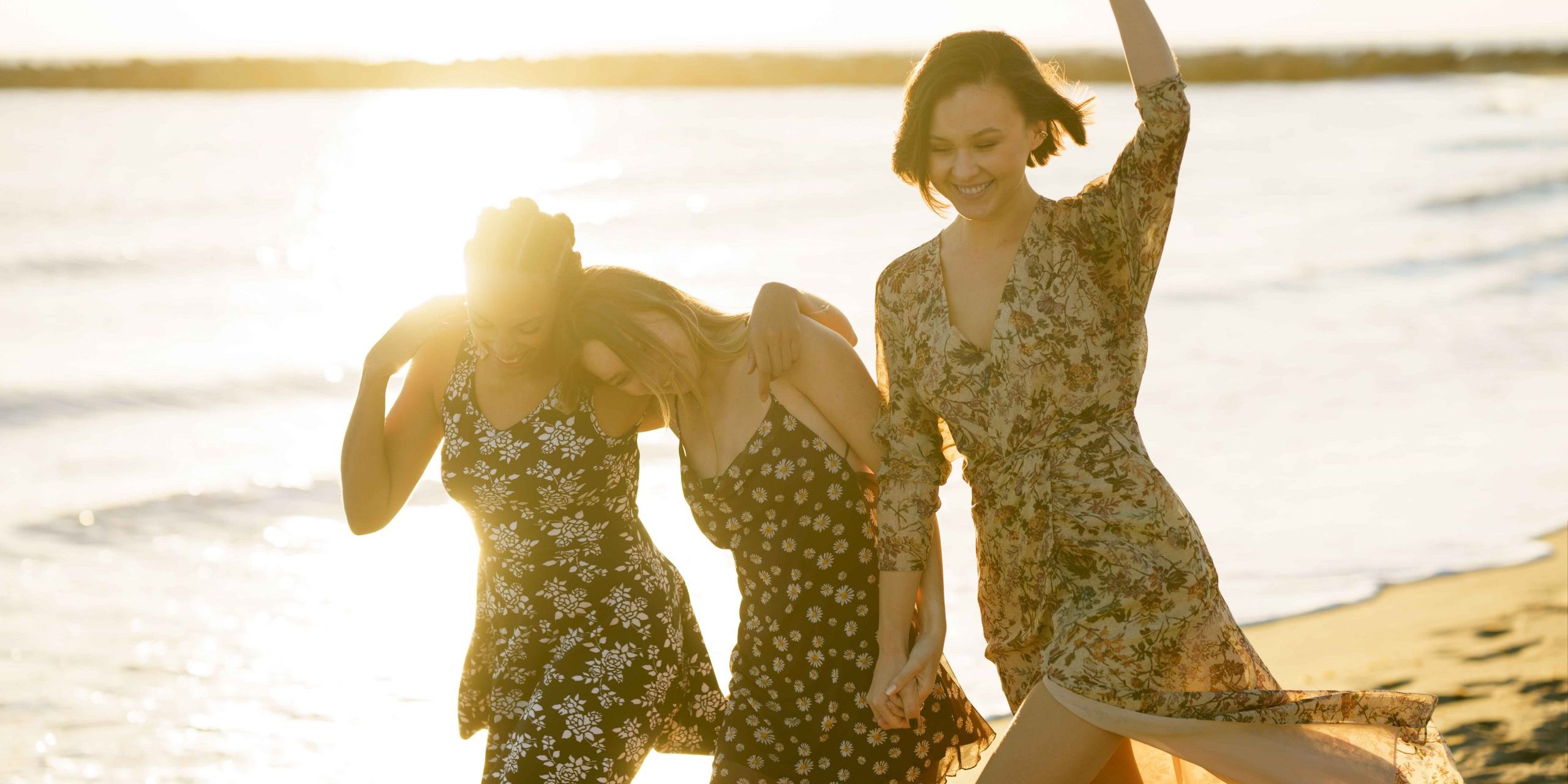 Happy diverse girlfriends walking on beach