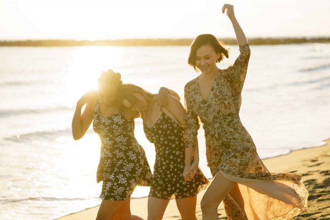Happy diverse girlfriends walking on beach