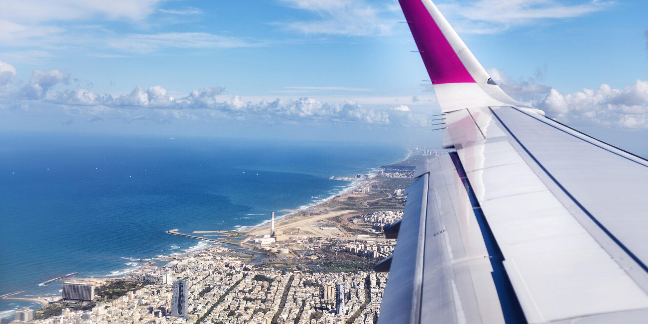 Top view from landing airplane. Window plane with copy space. Aerial view of cloud, sea, ocean and city landscape