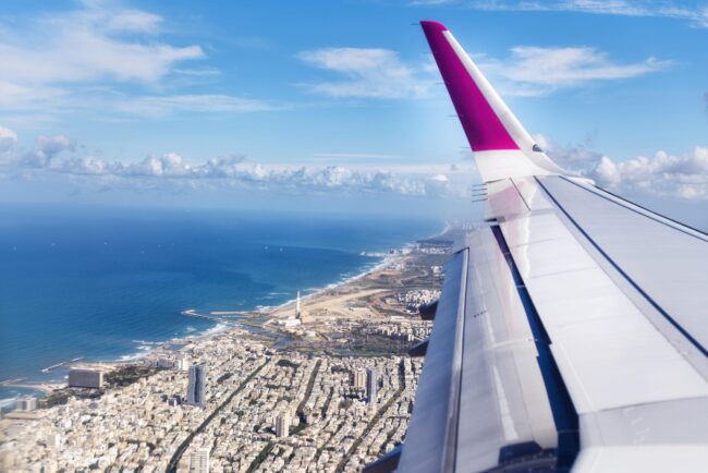 Top view from landing airplane. Window plane with copy space. Aerial view of cloud, sea, ocean and city landscape